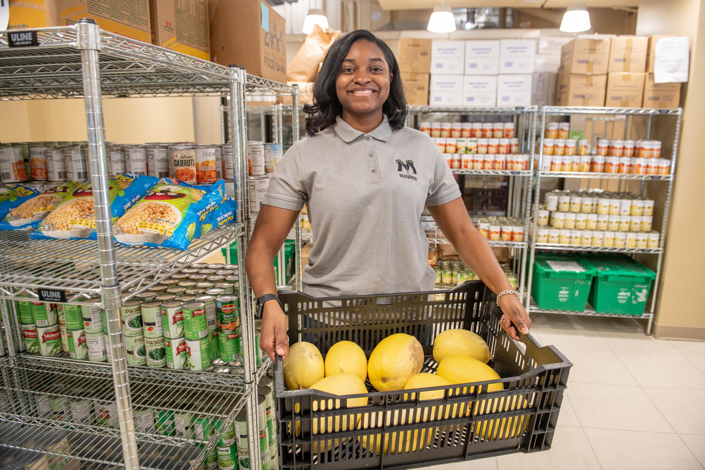 A food rescue volunteer located inside a food pantry, holding a basket of squash